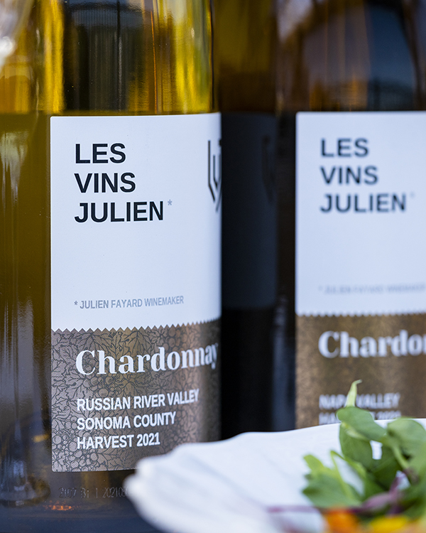 Bottle of Les Vins Julien Chardonnay wine sitting on table with a salad.