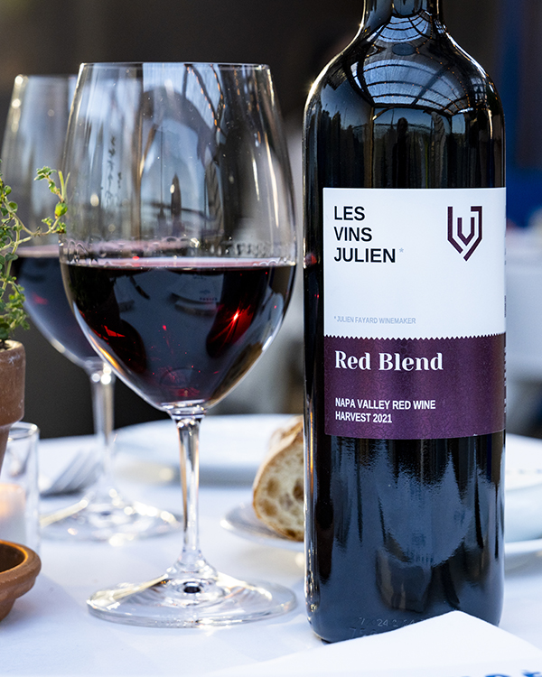 Bottle of Les Vins Julien Red Blend wine sitting on table with a glass of wine and some bread.